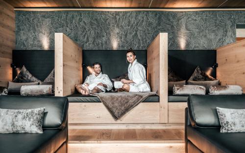 two men sitting on a bed in a room at Seehotel Panorama Relax in Resia