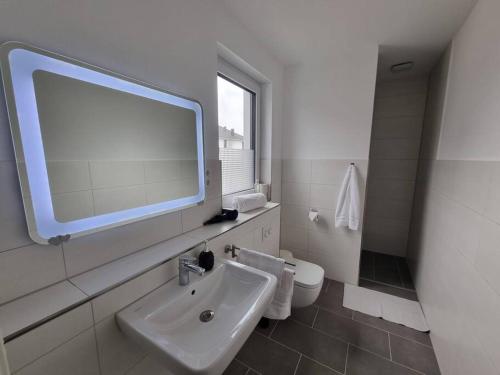 La salle de bains est pourvue d'un lavabo, de toilettes et d'un miroir. dans l'établissement New & Modern Apartment near Düsseldorf, à Willich