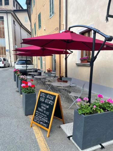 un café avec des parasols violets, des tables et des fleurs dans l'établissement Hotel Caffè Verdi - 24 hours Reception, à Pise