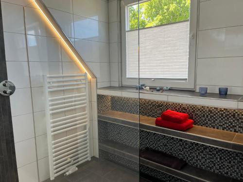 a bathroom with a shower with a red towel on a bench at Gästezimmer Am Haarhaus in Ostbevern