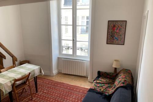 un salon avec une table et une fenêtre dans l'établissement 21m tout confort pour 2 proche des Remparts, à Vannes