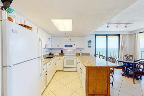 una cucina con frigorifero e tavolo con sedie di Phoenix Vacation Rentals a Orange Beach