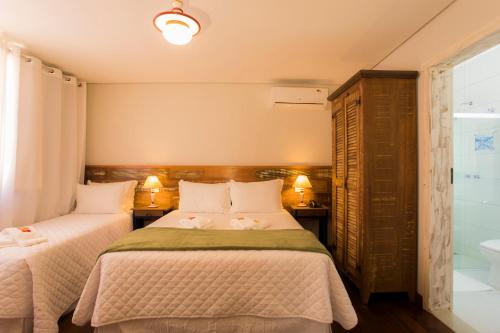 a bedroom with two beds and a bath tub at Pousada Ouro de Minas in Tiradentes