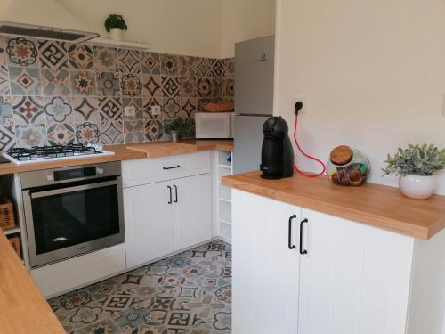 a kitchen with white cabinets and a stove top oven at La CABANE AUX ECREVISSES - LES PIEDS DANS L'EAU in Châteauneuf-les-Bains