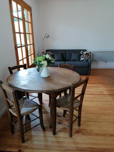 une table en bois avec des chaises et un vase avec des fleurs dans l'établissement La CABANE AUX ECREVISSES - LES PIEDS DANS L'EAU, à Châteauneuf-les-Bains