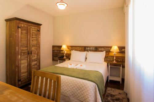 a bedroom with a bed and a dresser at Pousada Ouro de Minas in Tiradentes