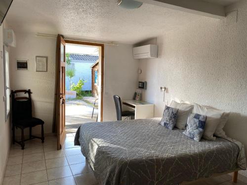 a bedroom with a bed and a table and a desk at LOGIS Hôtel La Chaumière in Marseillan