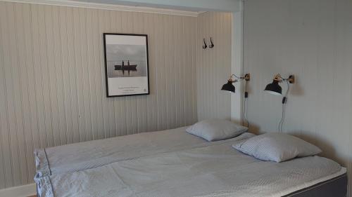 a bed in a bedroom with a picture on the wall at Vandrarhemmet Tallbacka/Ängelsberg Hostel in Ängelsberg