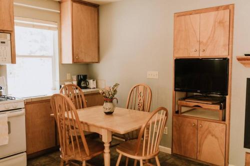 a kitchen with a wooden table with chairs and a television at The Long Barn Lodge in Long Barn