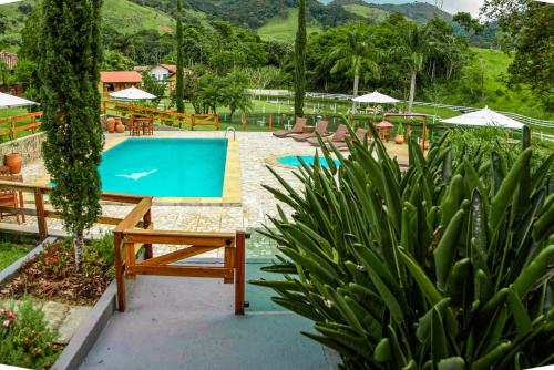 a pool with benches and umbrellas at a resort at Minha Glória Hotel Boutique in Bom Jardim