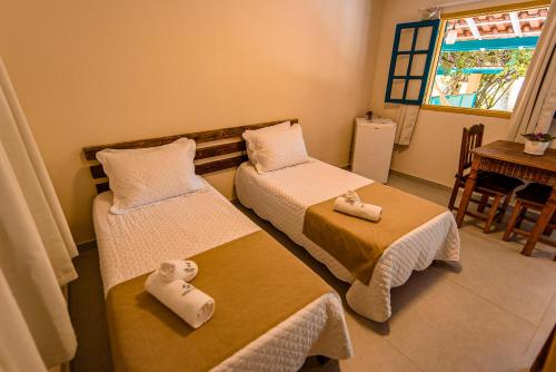 a room with two beds and a table and a window at Minha Glória Hotel Boutique in Bom Jardim