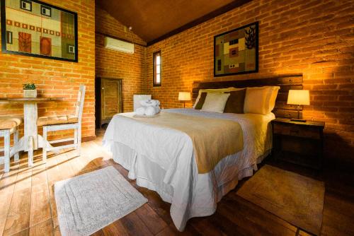 a bedroom with a bed and a brick wall at Minha Glória Hotel Boutique in Bom Jardim