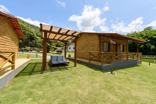 a wooden cabin with a bench in the yard at Minha Glória Hotel Boutique in Bom Jardim