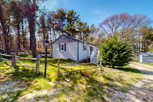 a tiny house in a field with a fence at Whitman Surf Cottage & Great Hollow Retreat in Truro