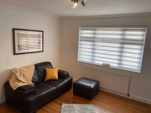 a living room with a leather couch and a window at One bed cozy flat in Dartford