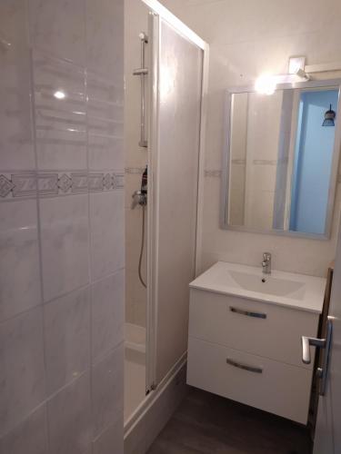 a white bathroom with a sink and a shower at Appartement restauré à 50 m de la plage in Saint-Hilaire-de-Riez