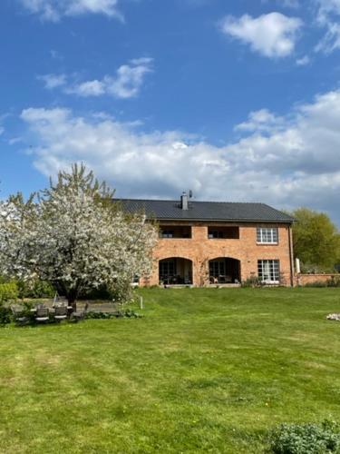 une grande maison en briques avec un arbre dans un champ dans l'établissement Ars Vivendi, à Strasen