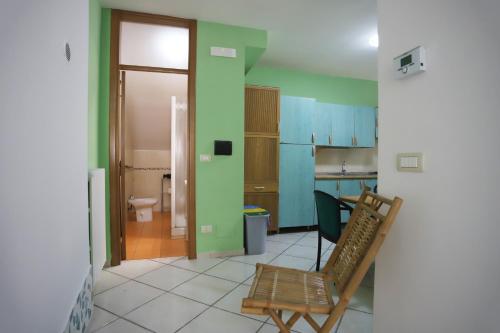 a room with a chair and a kitchen with green walls at PALAZZO PELLEGRINO vietri in Vietri sul Mare