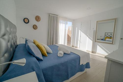 a bedroom with a blue bed with a blue blanket at Precioso ático con vistas al mar Parking gratuito in Corralejo
