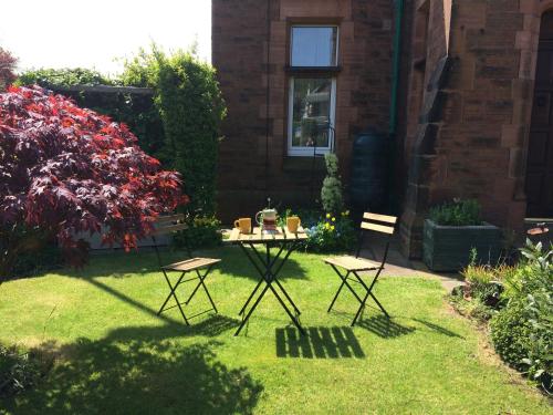 a garden with two chairs and a table in the grass at Stylish Apartment in Stone-Built Former Rectory in Penrith