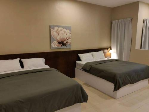 1 dormitorio con 2 camas y un cuadro en la pared en T House Nearby Kuantan East Coast Shopping Mall, en Kuantan