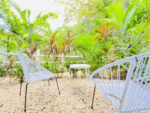 two white chairs and a table in a garden at Altamar in Santa Teresa Beach