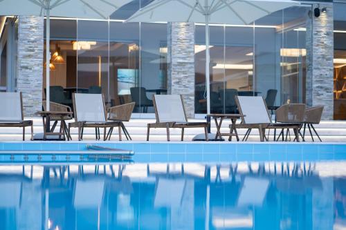 a pool with chairs and tables next to a building at Panorama Hill Hotel in Iraklitsa