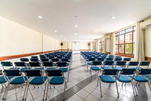 a large room with blue chairs in a building at Itapetinga Hotel in Atibaia