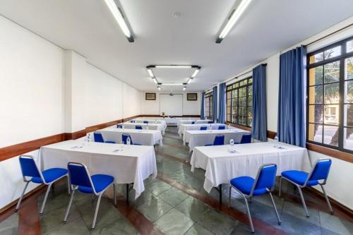 a large room with white tables and blue chairs at Itapetinga Hotel in Atibaia
