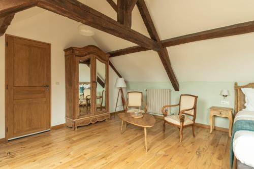 a bedroom with a bed and a table and chairs at L'Ecurie Gourmande in Thaon