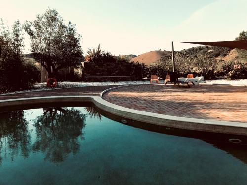 a pool of water next to a patio with a bench at casa paz tavira in Tavira