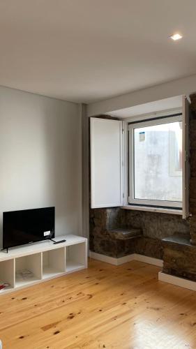 a living room with a tv and a window at São Bartolomeu Apartment 1 in Coimbra