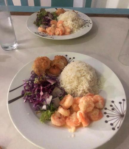 two plates of food on a table with rice and shrimp at Villa Manoir in Anse Lazio