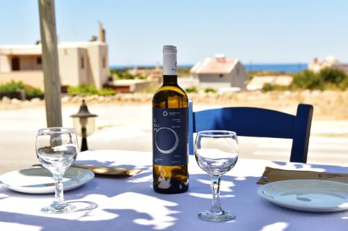 una bottiglia di vino seduta su un tavolo con bicchieri di Rooms Kochilas Elafonisi a Elafonisi