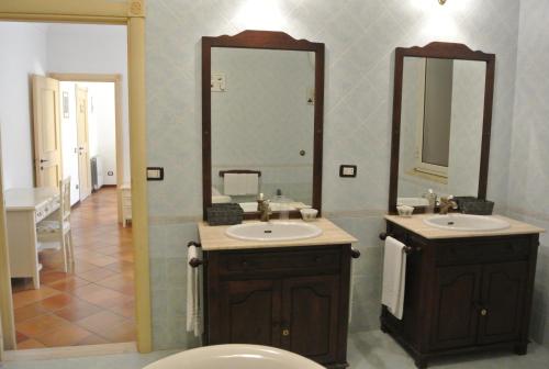 a bathroom with a toilet and two sinks and a mirror at Villa Carlotta Resort in San Leone