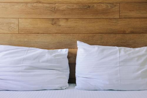 two white pillows on a bed with a wooden headboard at D and D hotel in Tbilisi City