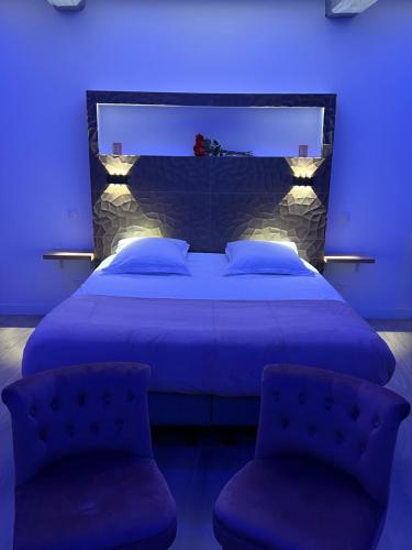1 dormitorio azul con 1 cama grande y 2 sillas en Suite & Jacuzzi, en Givors