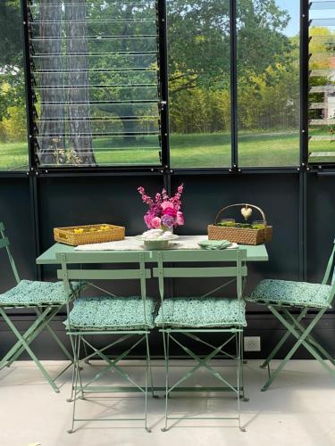 une table avec deux chaises et une table avec des fleurs. dans l'établissement Le Celadon, à Montaigu-Vendée