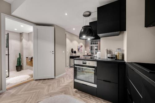 a kitchen with black cabinets and a stove top oven at Cozy room in City center in Trondheim