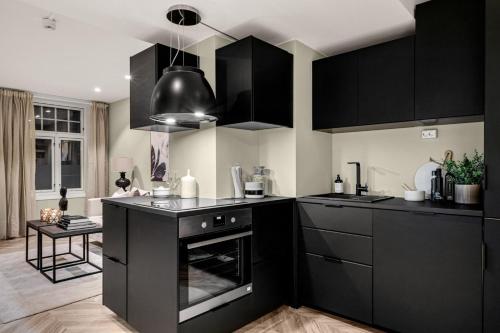 a kitchen with black cabinets and an oven at Cozy room in City center in Trondheim
