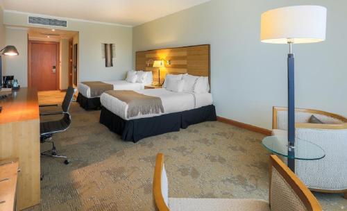a hotel room with two beds and a desk at Sonesta Hotel Osorno in Osorno