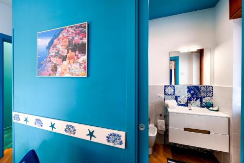 a bathroom with a blue door with a painting on the wall at Sofì Sorrento Suites in Sorrento