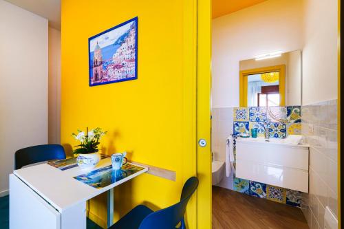 a yellow room with a desk and a bathroom at Sofì Sorrento Suites in Sorrento