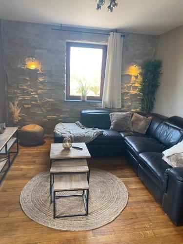 a living room with a black leather couch and a table at Mon petit cocon in Jalhay