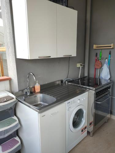 een keuken met een wastafel en een wasmachine bij Casa Polly in Follonica