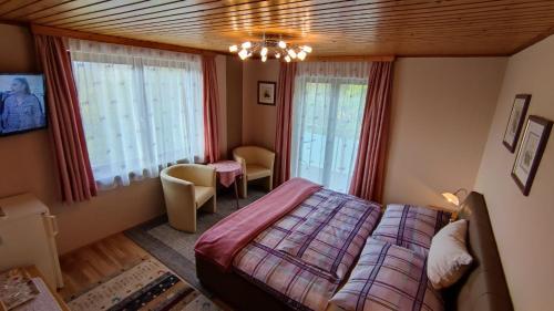 a bedroom with a bed and two windows at Ferienparadies Gutounik in Pörtschach am Wörthersee