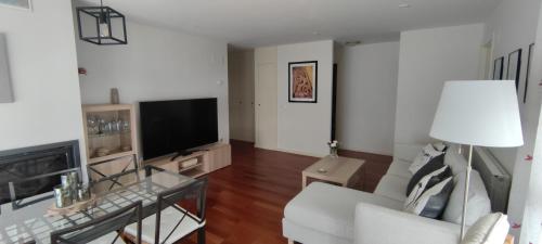 sala de estar con sofá blanco y TV en Apartamento Sabiñanigo Las Margas Pirineos, golf y piscina en Sabiñánigo