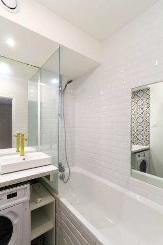 ein weißes Badezimmer mit einer Badewanne und einem Waschbecken in der Unterkunft Bright Studio Of 29m With Wifi Near Paris in Issy-les-Moulineaux