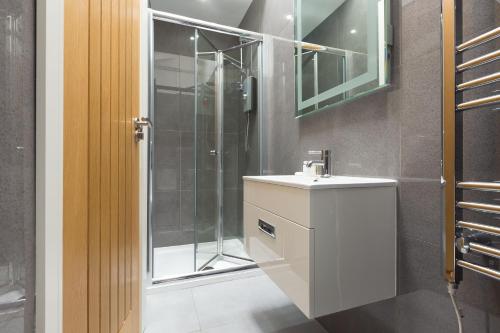 een badkamer met douche, wastafel en spiegel bij Little Gem in St Ives