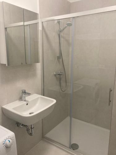 a shower with a glass door next to a sink at Bellevue Apartments in Izola